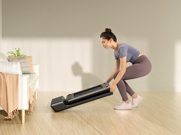 Woman folding a compact walking pad for easy storage in a small apartment