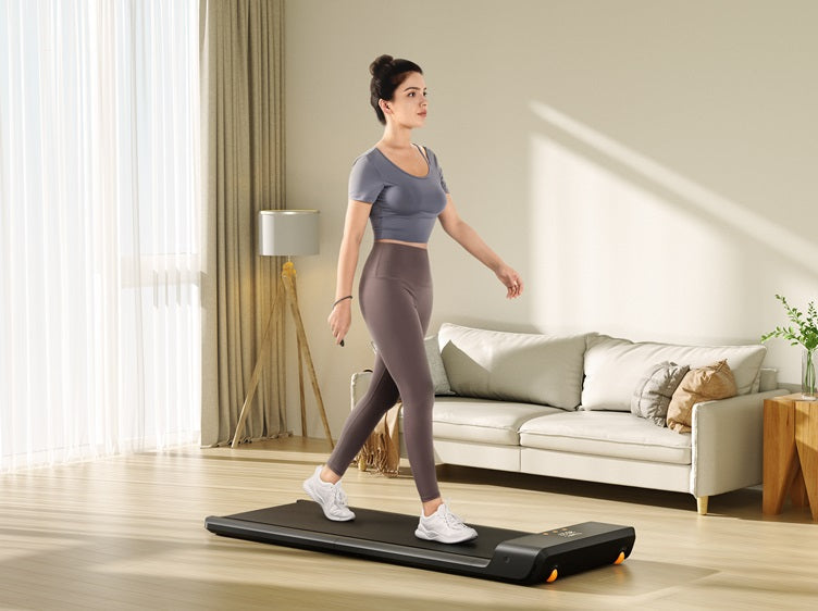 Woman walking on a compact walking pad in a bright home living room